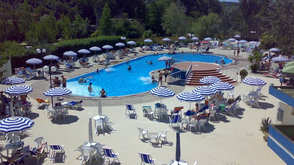 A large outdoor swimming pool surrounded by lounge chairs and umbrellas.
