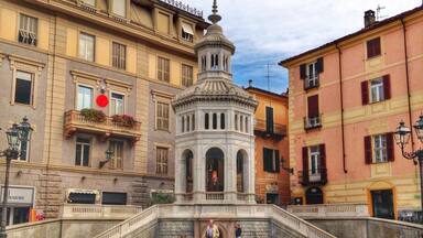 A historic fountain with a central statue, surrounded by classic European architecture.