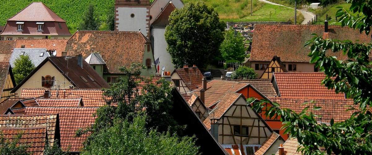 A village with a church tower, terraced vineyards, and traditional houses.