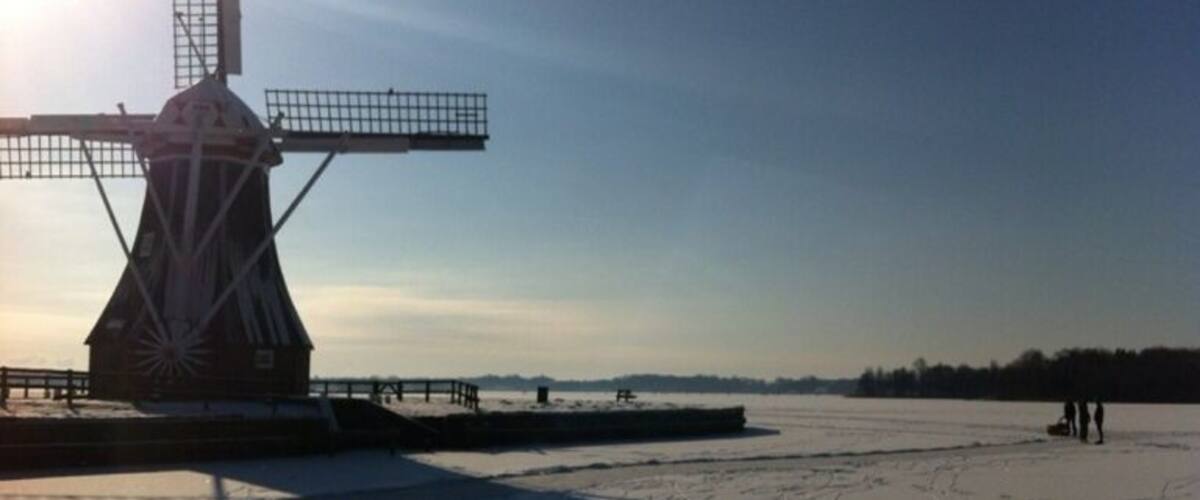 A windmill, a frozen lake, and a clear sky.