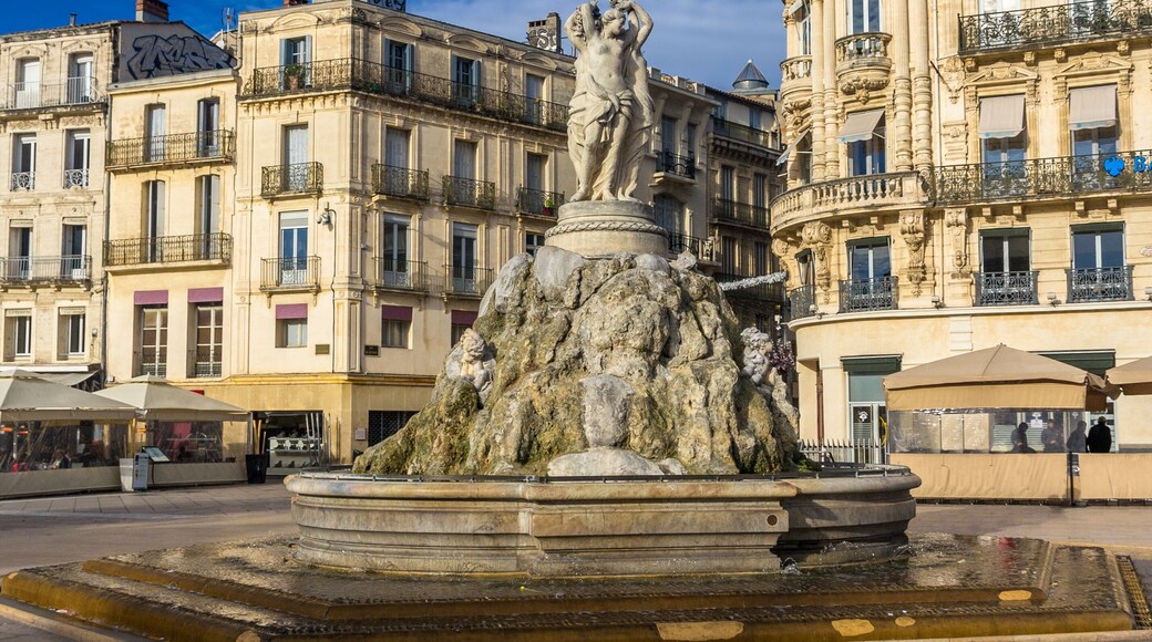 Una fuente con una estatua, rodeada de edificios históricos con balcones y una cúpula.