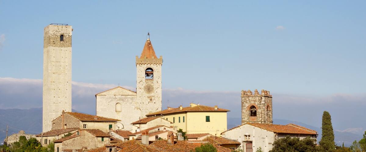 A historic town with a prominent church featuring a tall bell tower and a smaller adjacent tower.
