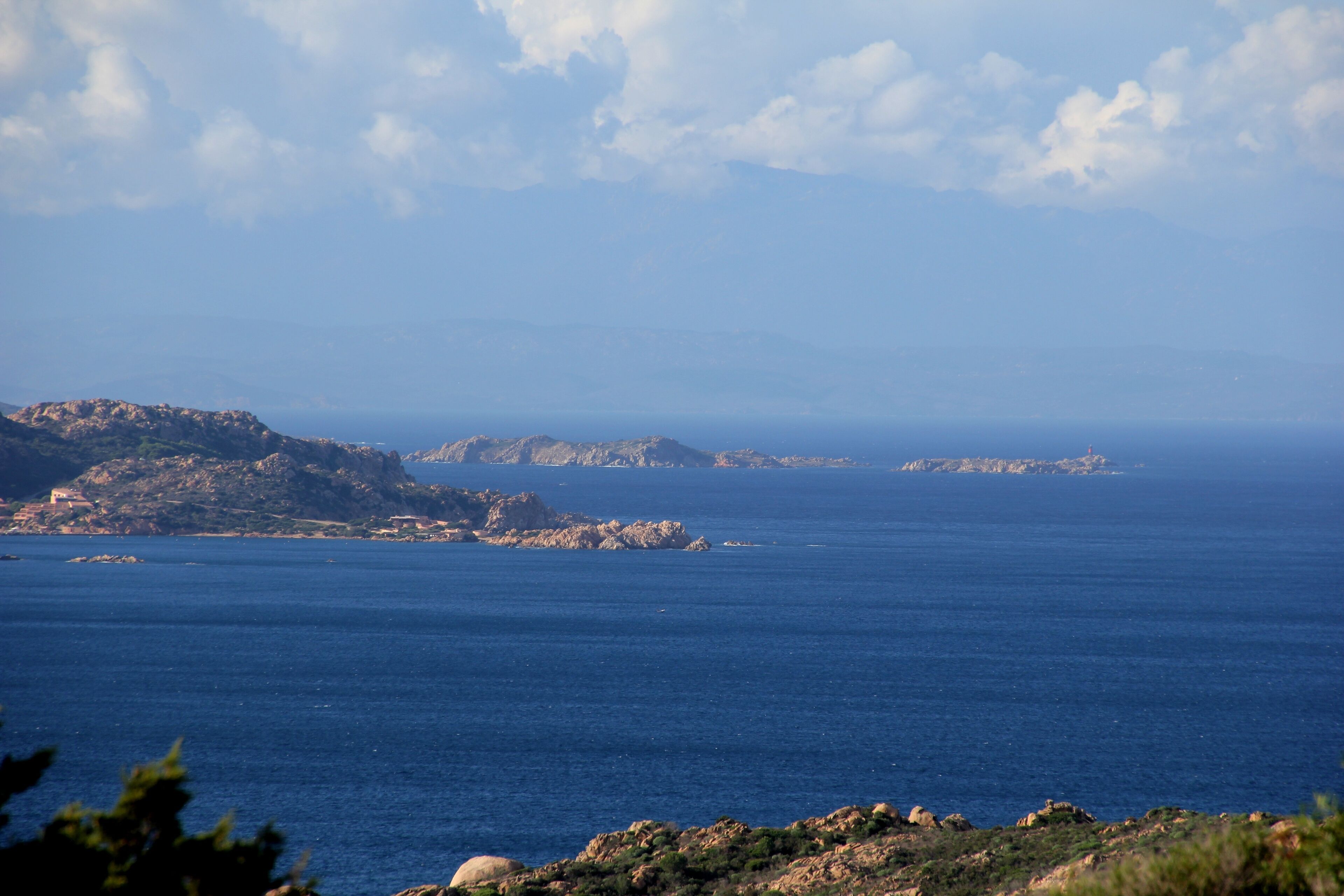 A coastal landscape with rocky terrain and calm blue waters.