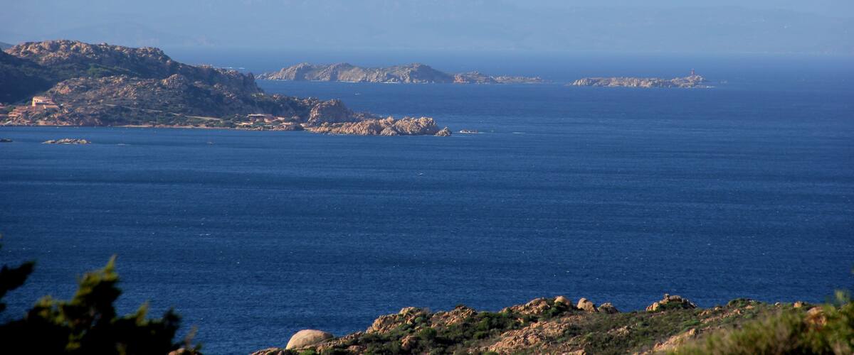 A coastal landscape with rocky terrain and calm blue waters.