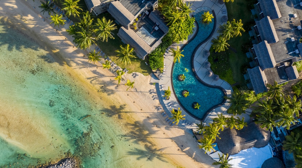 Een overzicht vanuit de lucht van een resort met een zwembad, palmbomen en een strand.