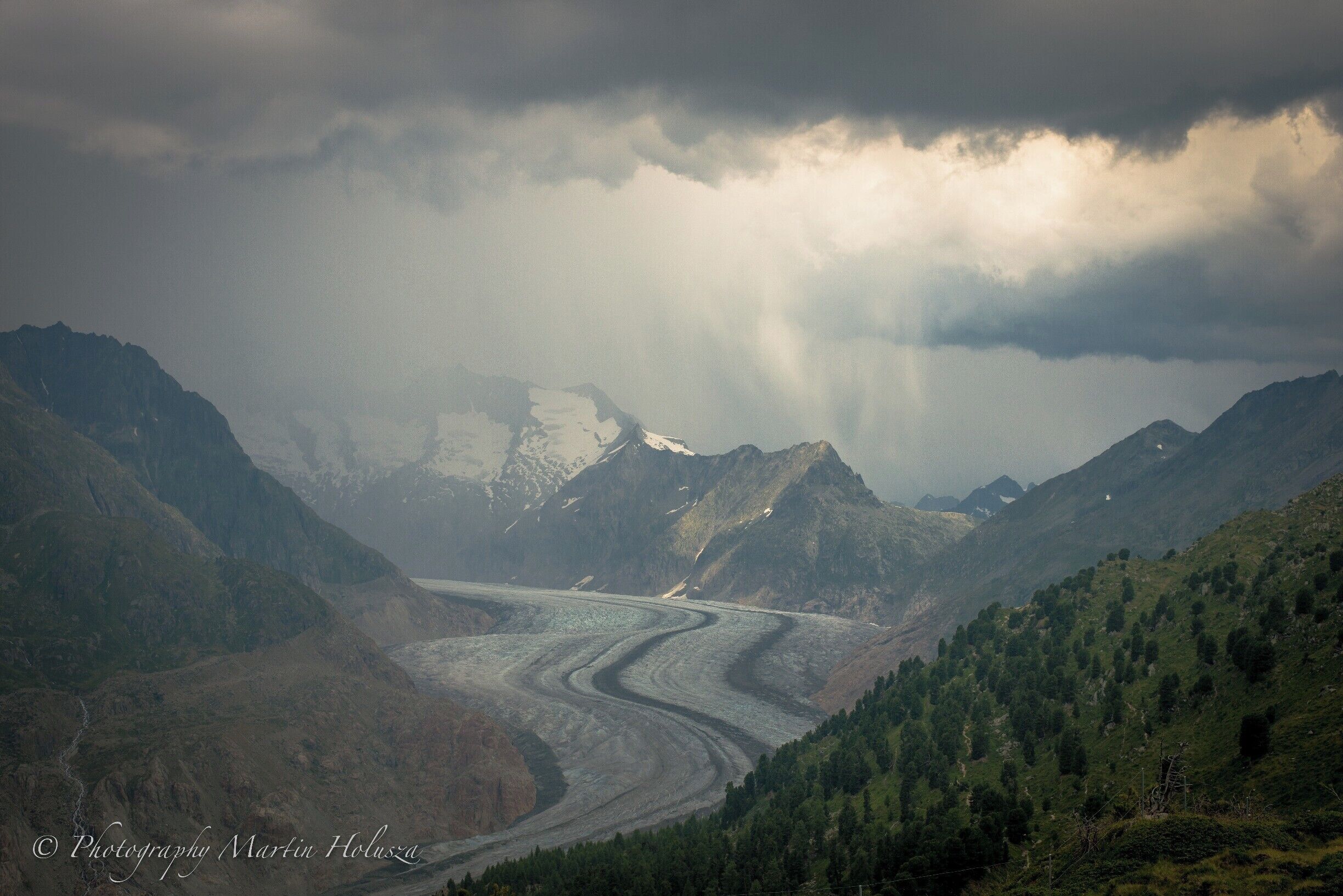 The Aletsch Glacier or Great Aletsch Glacier is the largest glacier in the Alps. It has a length of about 23 km (14 mi) (2014),has about a volume of 15.4 km3 and covers about 81.7 km2 in the eastern Bernese Alps in the Swiss canton of Valais. The Aletsch Glacier is composed of four smaller glaciers converging at Concordia Place, where its thickness was measured by the ETH to be still near 1 km. It then continues towards the Rhône valley before giving birth to the Massa. The Aletsch Glacier is – like most glaciers on this world – a retreating glacier. Amazing place for a day trip or long distance hike. Many cable cars around so easy access for lazy ppl.
https://www.youtube.com/watch?v=2vwO6ulzBk8&t=143s
Thanks for watching&subscribing