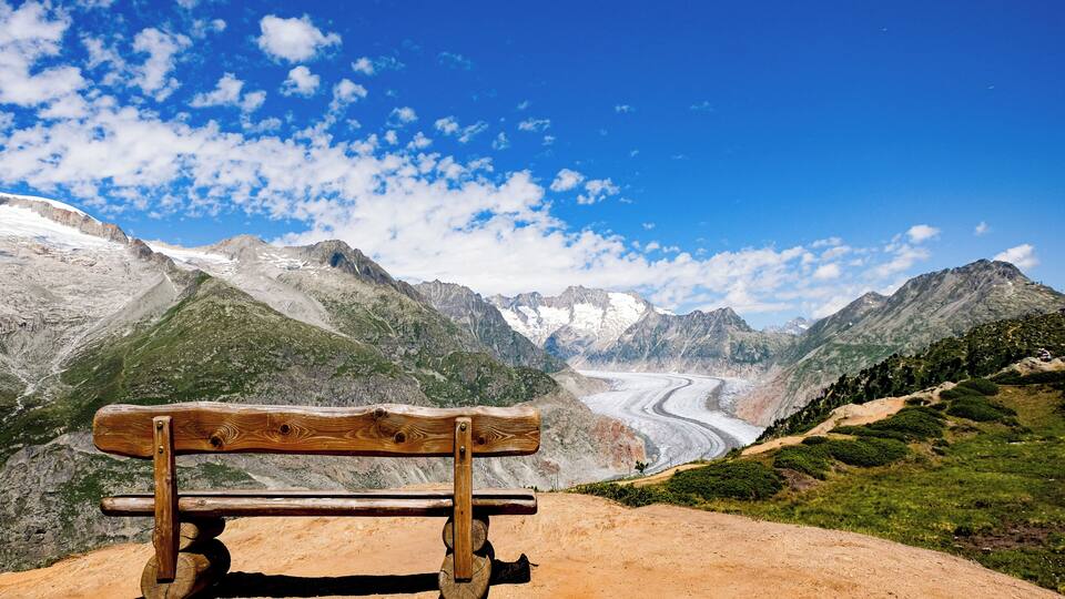 A wooden bench overlooking a glacier and mountains.