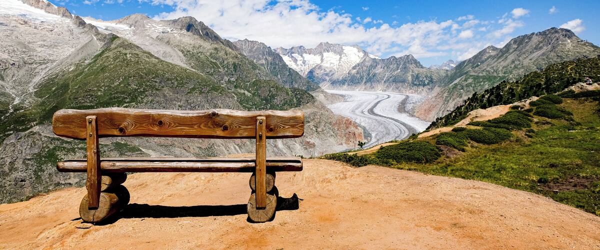 A wooden bench overlooking a glacier and mountains.