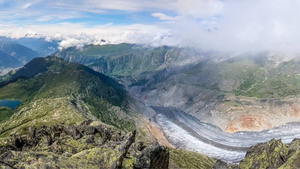 A mountain landscape with a glacier, rocky terrain, and a small lake.