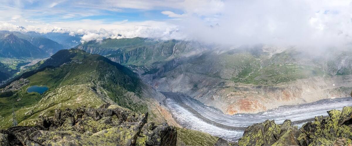 A mountain landscape with a glacier, rocky terrain, and a small lake.