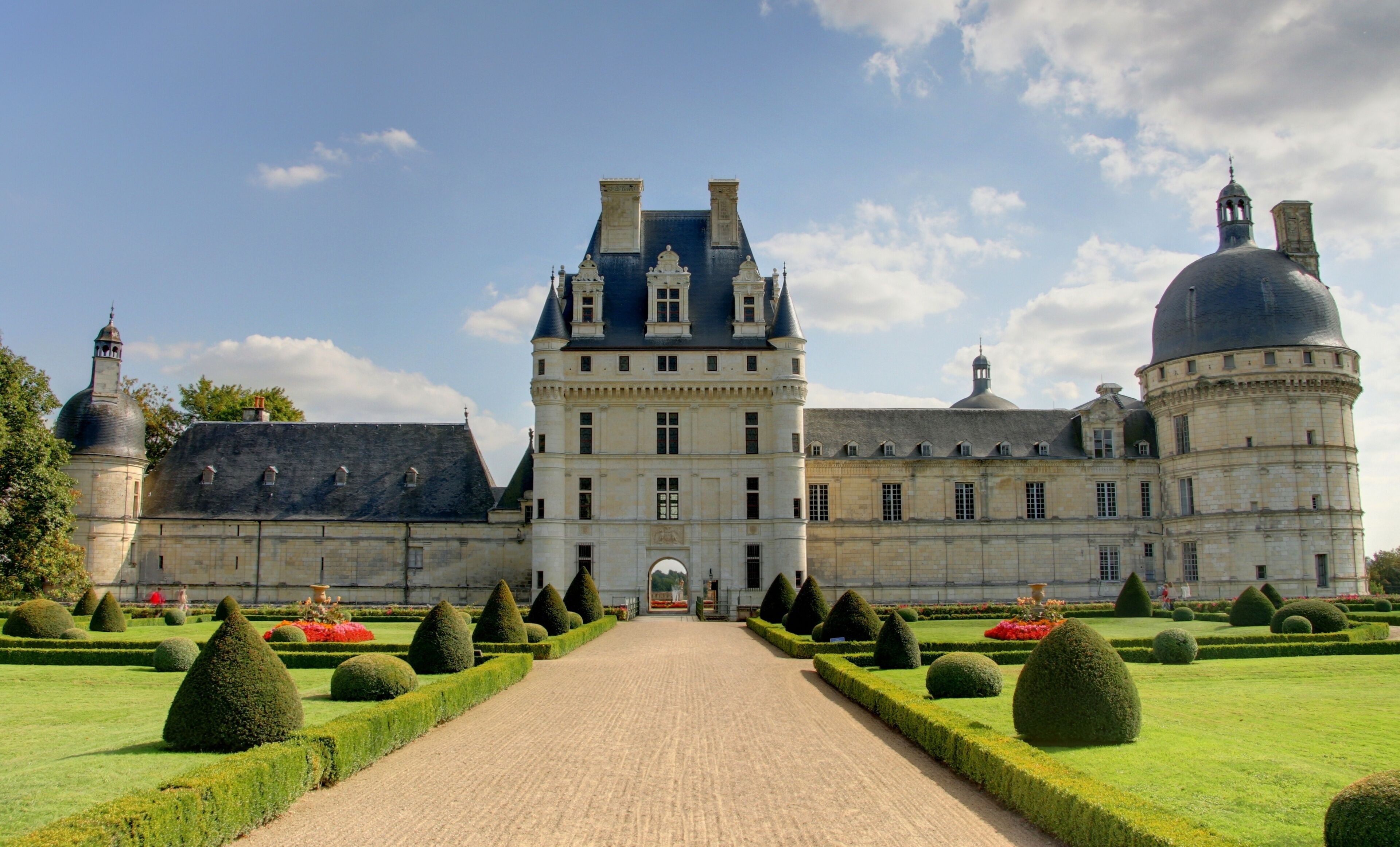 A grand château with a symmetrical garden, a central courtyard, and a large dome.