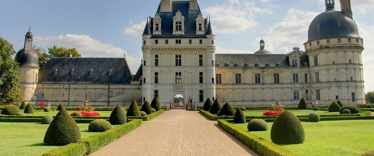 A grand château with a symmetrical garden, a central courtyard, and a large dome.