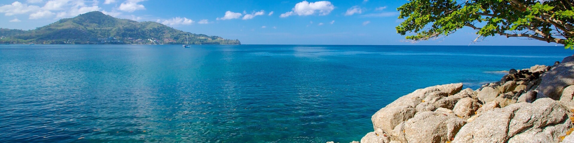 A clear blue sea, rocky coastline, and a distant mountain.