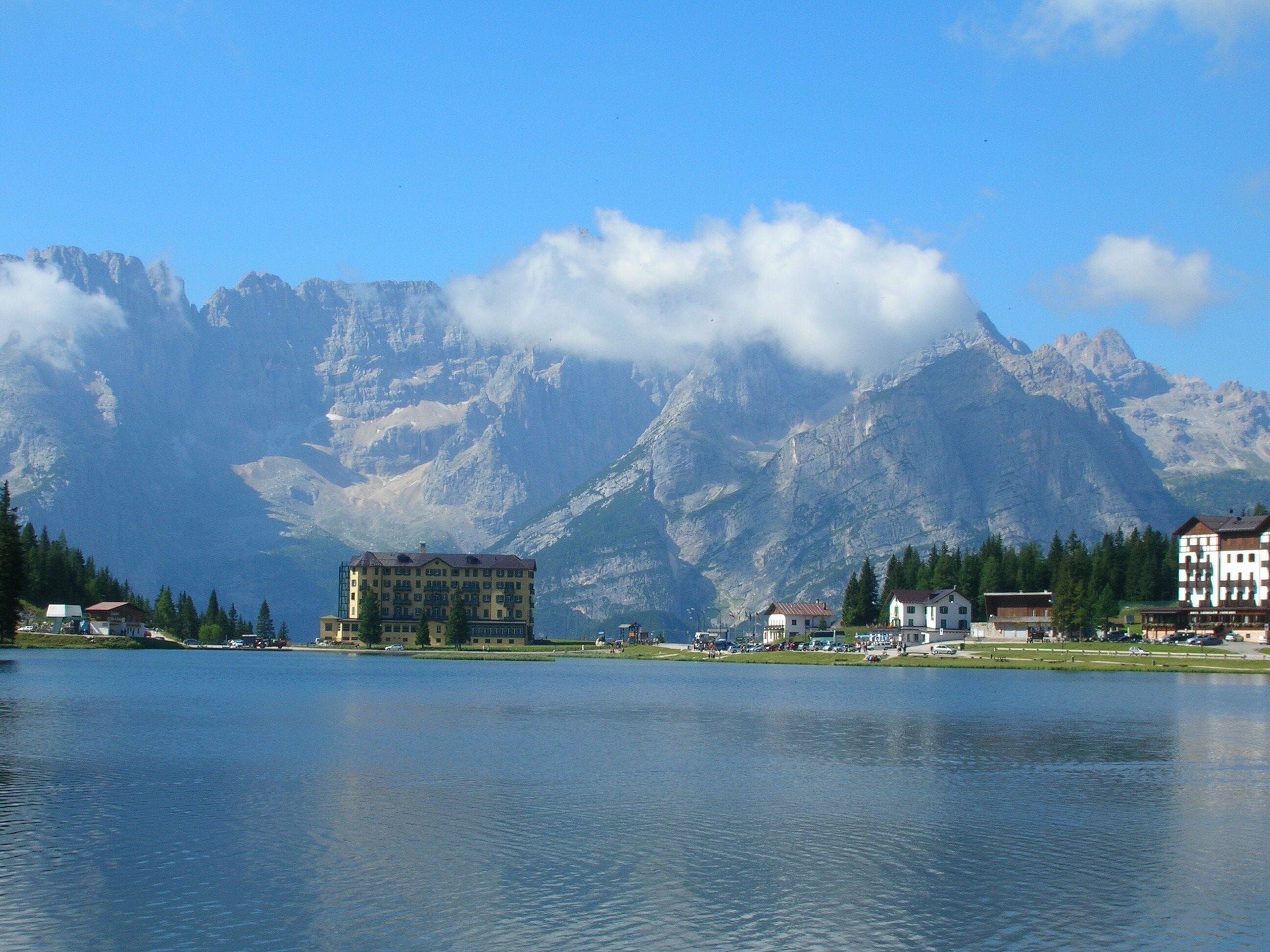 A lake with buildings and mountains in the background.