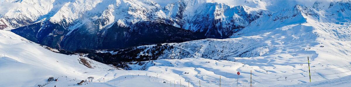 Ein verschneites Gebirge mit Skipisten und einer Seilbahn.