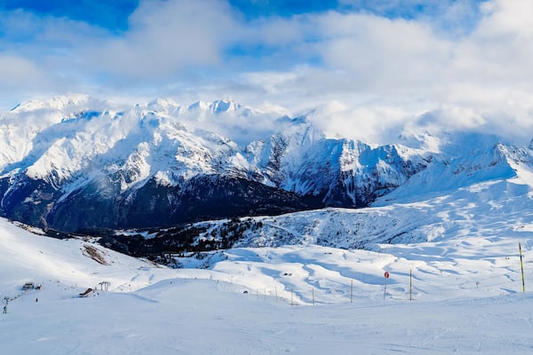 Une chaîne de montagnes enneigée, avec des pistes de ski et un télésiège.