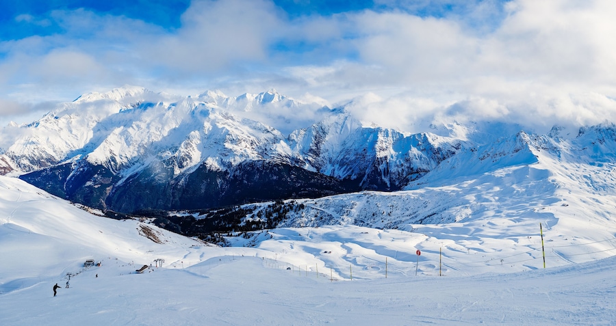 A snow-covered mountain range with ski slopes and a ski lift.