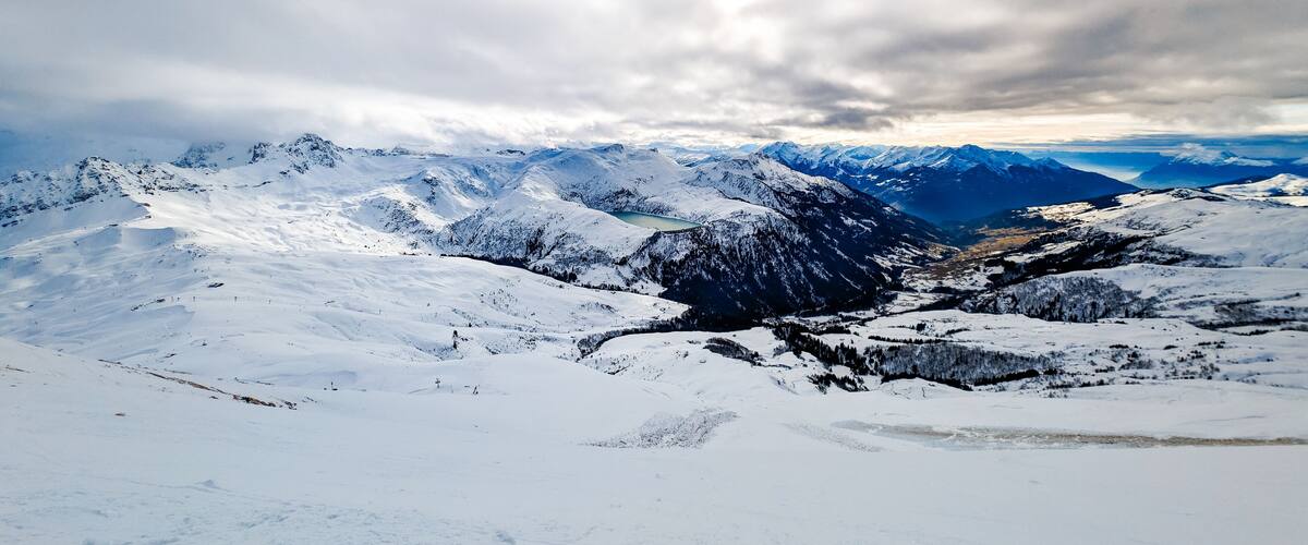A snow-covered mountain range with a valley and a lake.