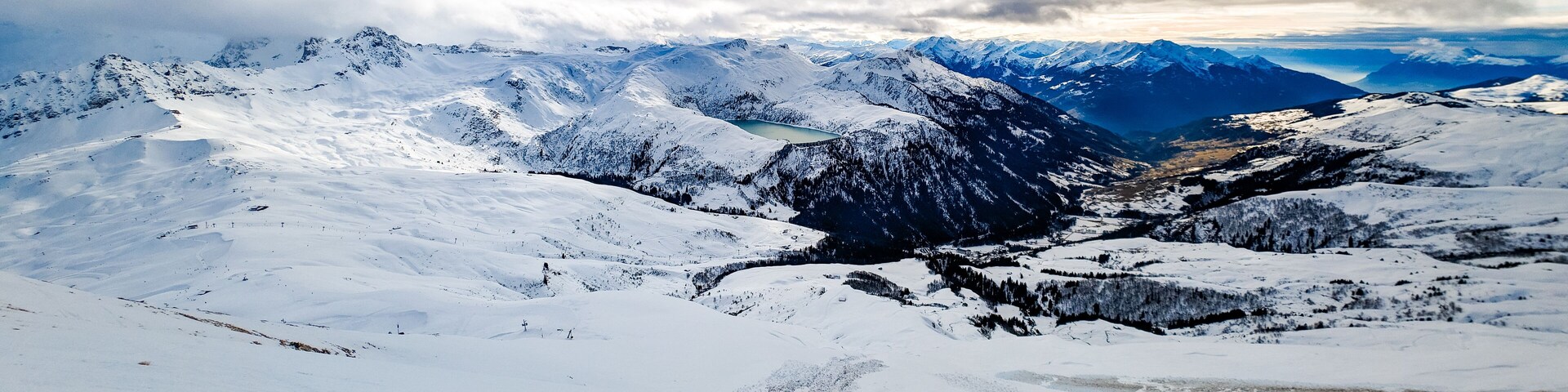 A snow-covered mountain range with a valley and a lake.