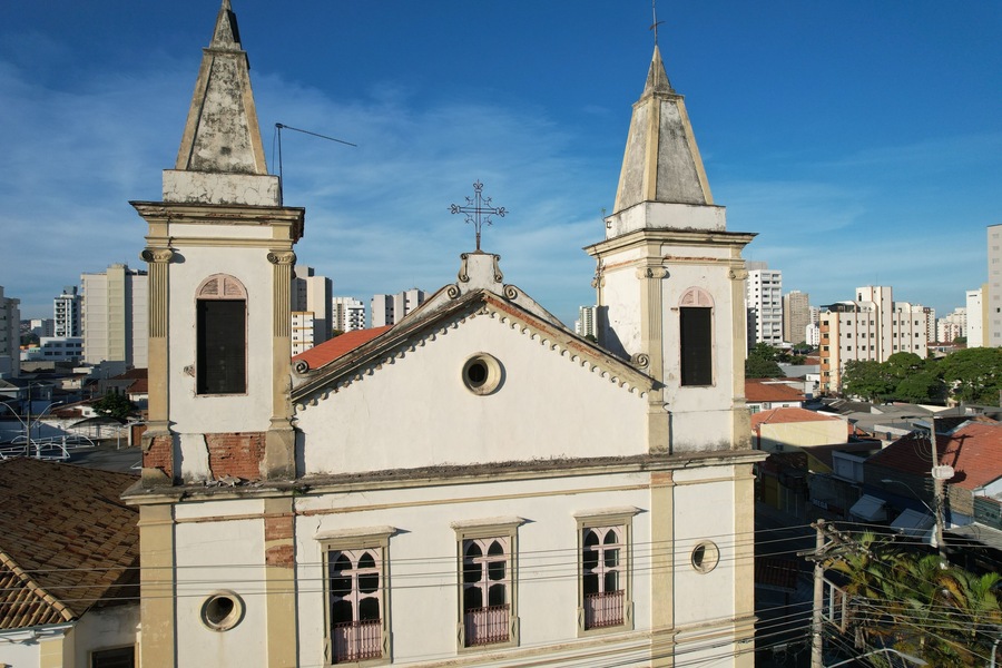 Uma igreja com duas torres e uma cruz no telhado, cercada por edifícios urbanos.