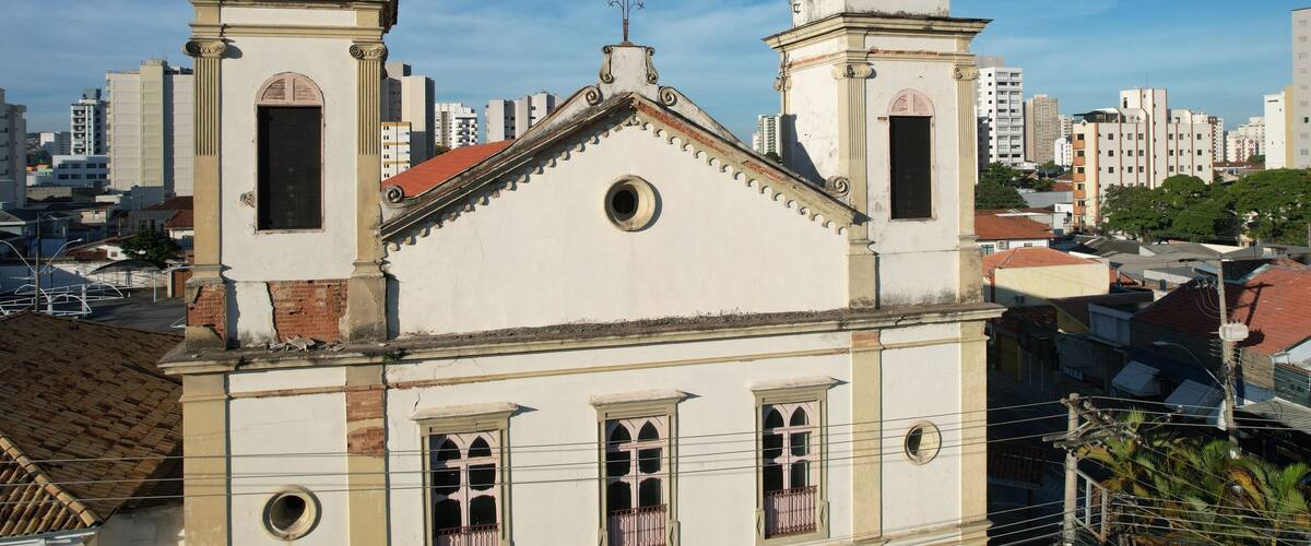 A church with two towers and a cross on the roof, surrounded by urban buildings.