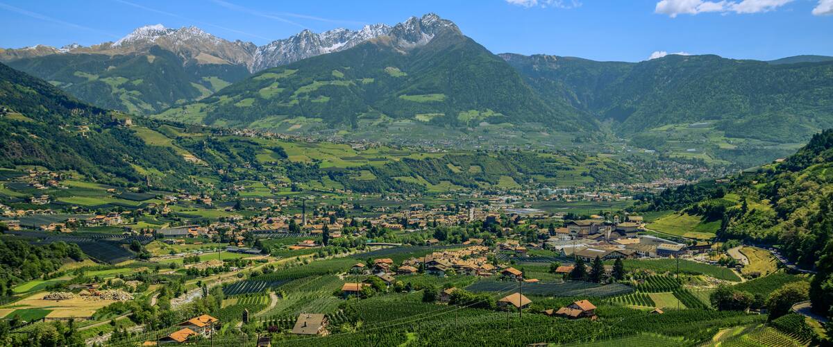 A valley with a town surrounded by mountains and fields.
