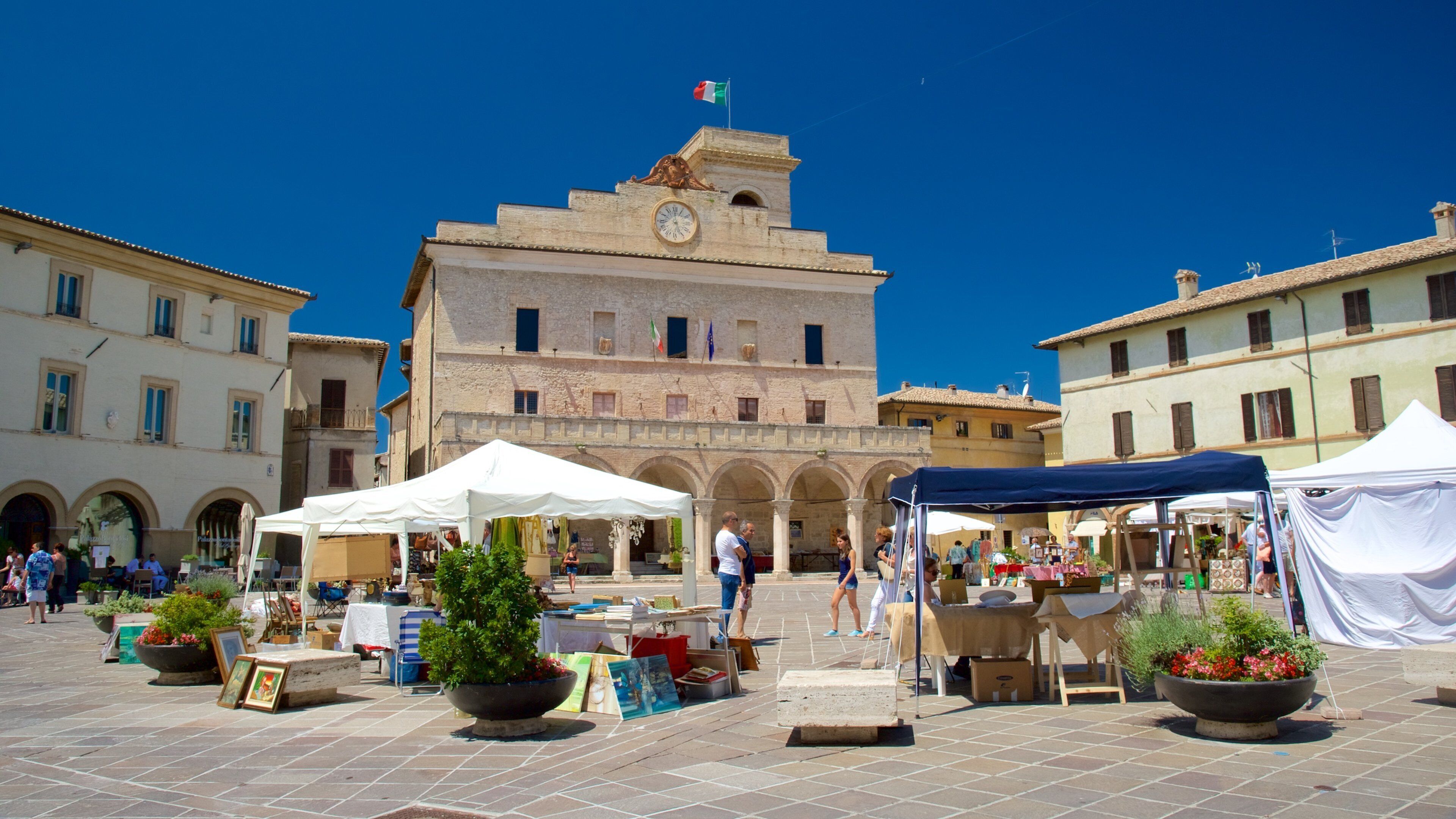 A historic square with a prominent clock tower, market stalls, and traditional architecture.