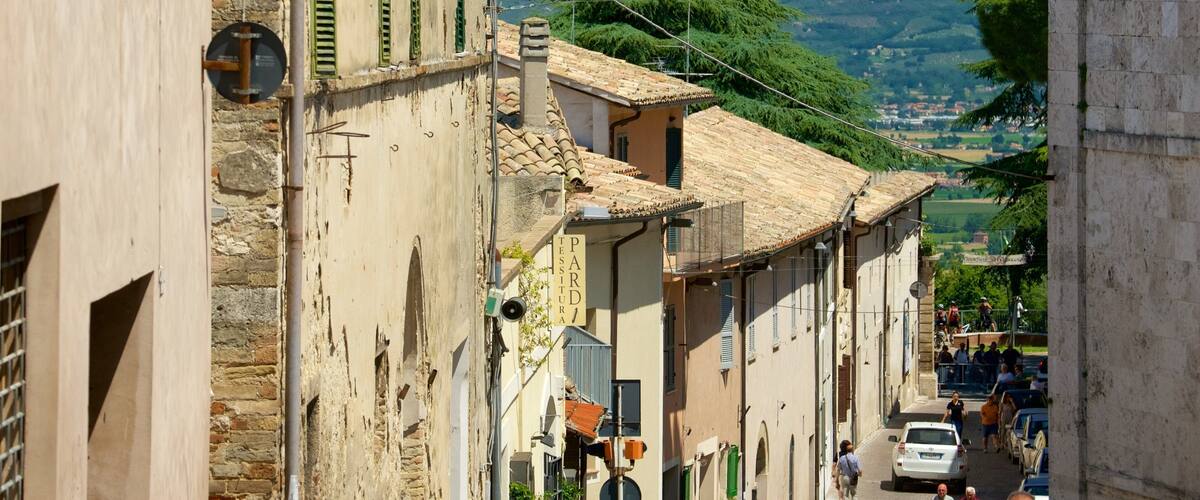 Una calle estrecha con edificios tradicionales, una montaña al fondo y algunas personas caminando.