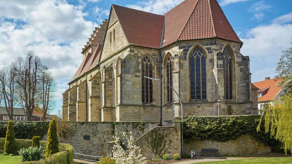 A historic stone church with a red-tiled roof and arched windows.