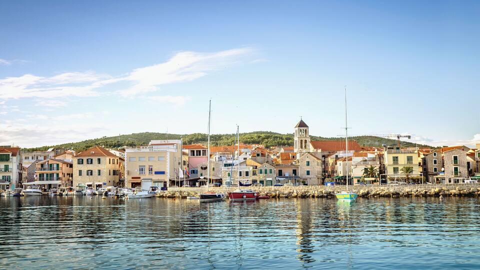 A coastal town with colorful buildings, a church, and boats docked along the waterfront.