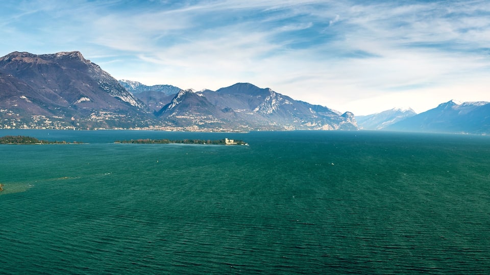 A large lake surrounded by mountains with a small island in the foreground.