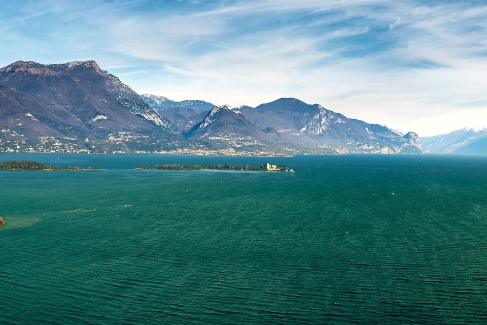 Ein großer See, umgeben von Bergen, mit einer kleinen Insel im Vordergrund.