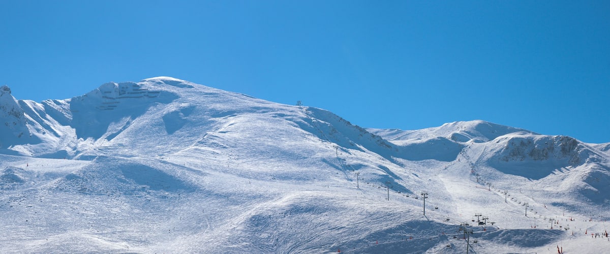 A snow-covered mountain with ski slopes and a clear blue sky.