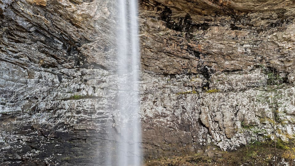 A waterfall cascading down a rocky cliff into a pool below.