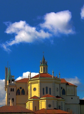 Una iglesia con techo de tejas rojas y aguja verde.