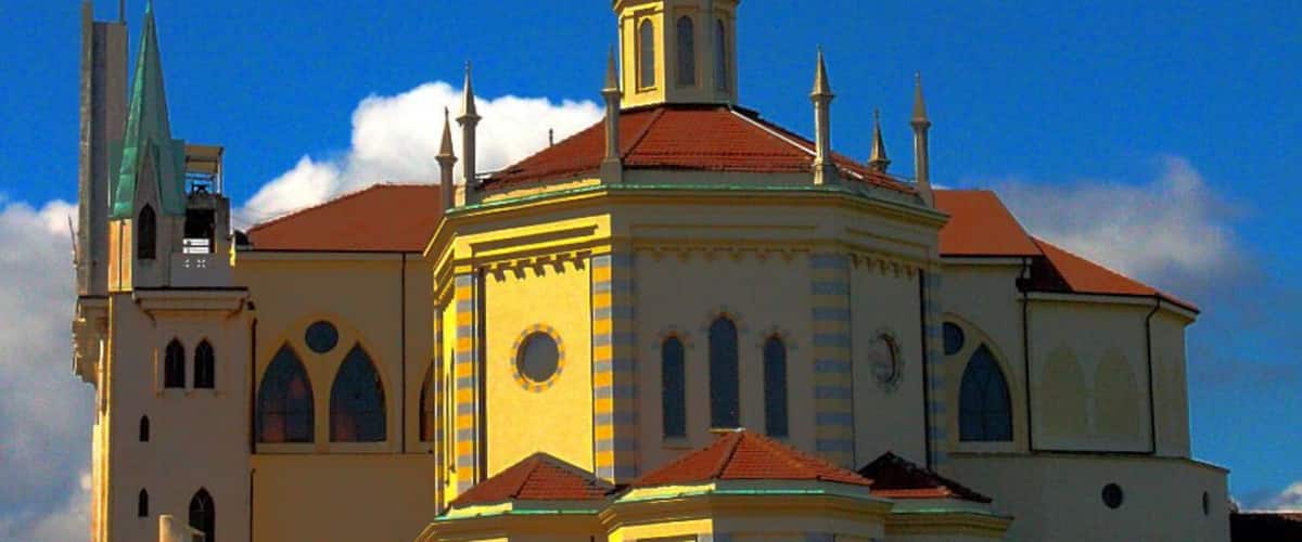 A church with a red-tiled roof and a green spire.