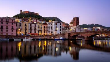 A historic town with a river, a bridge, and buildings reflecting on the water.