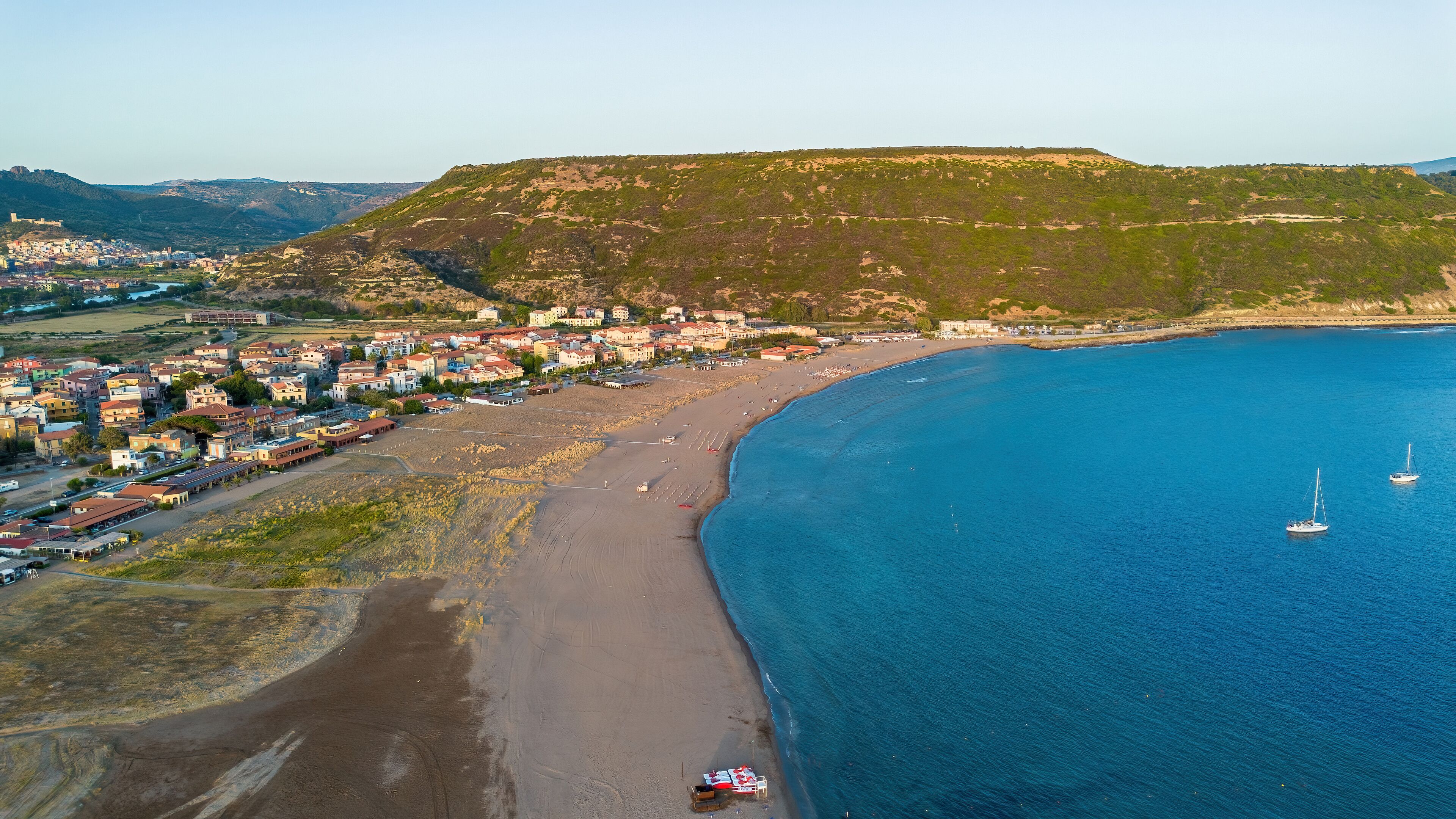 Aerial view of Bosa Marina beach and sailboats at sunset in Sardinia, Italy