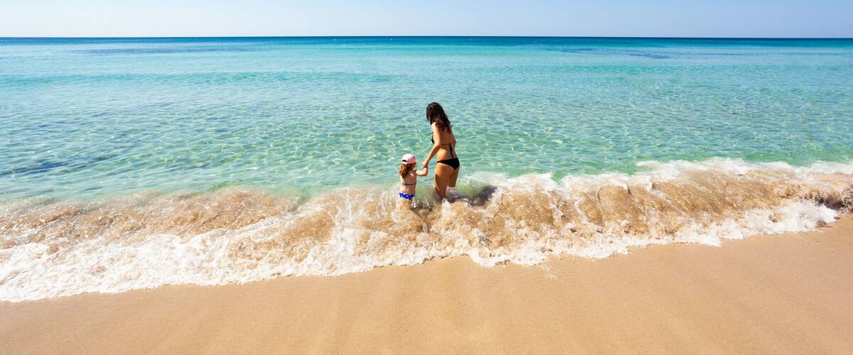 A beach with clear turquoise water and a sandy shore.