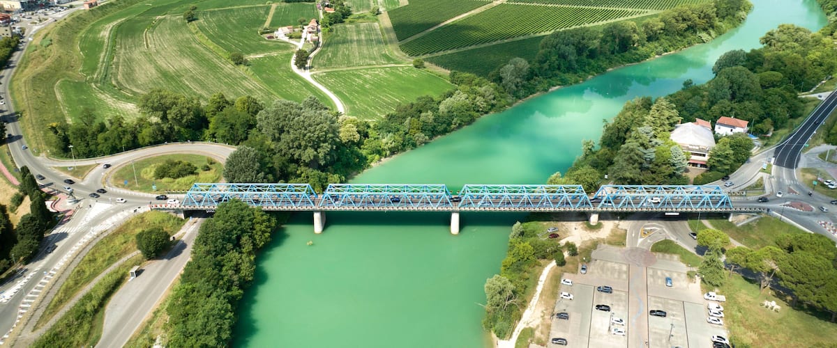 A bridge over a river, surrounded by green fields and a town in the background.