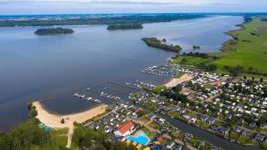Vista aérea de una zona residencial junto a un lago, con barcos, una playa y un puerto deportivo.