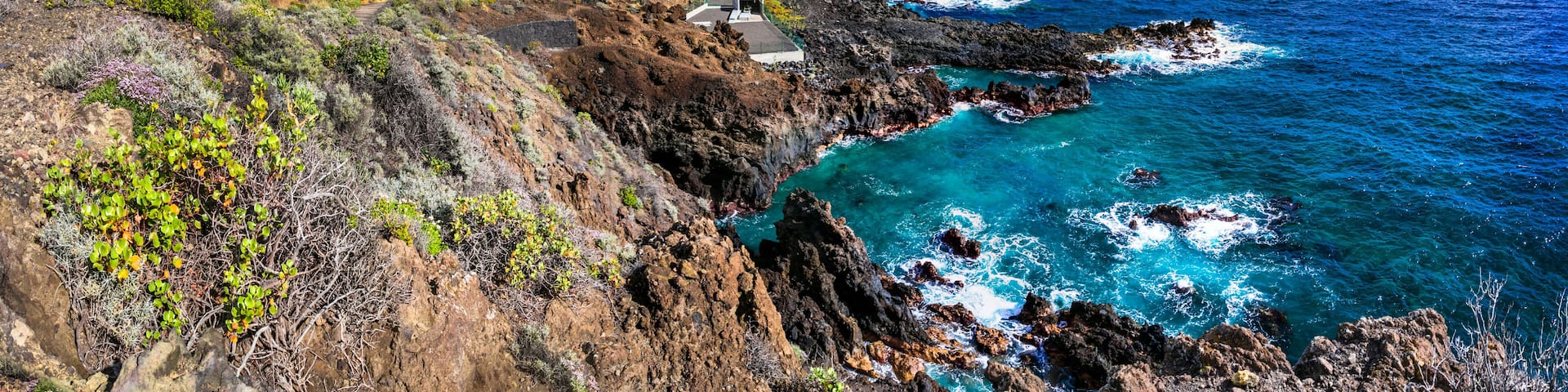 A coastal town with colorful buildings, rocky cliffs, and turquoise waters.