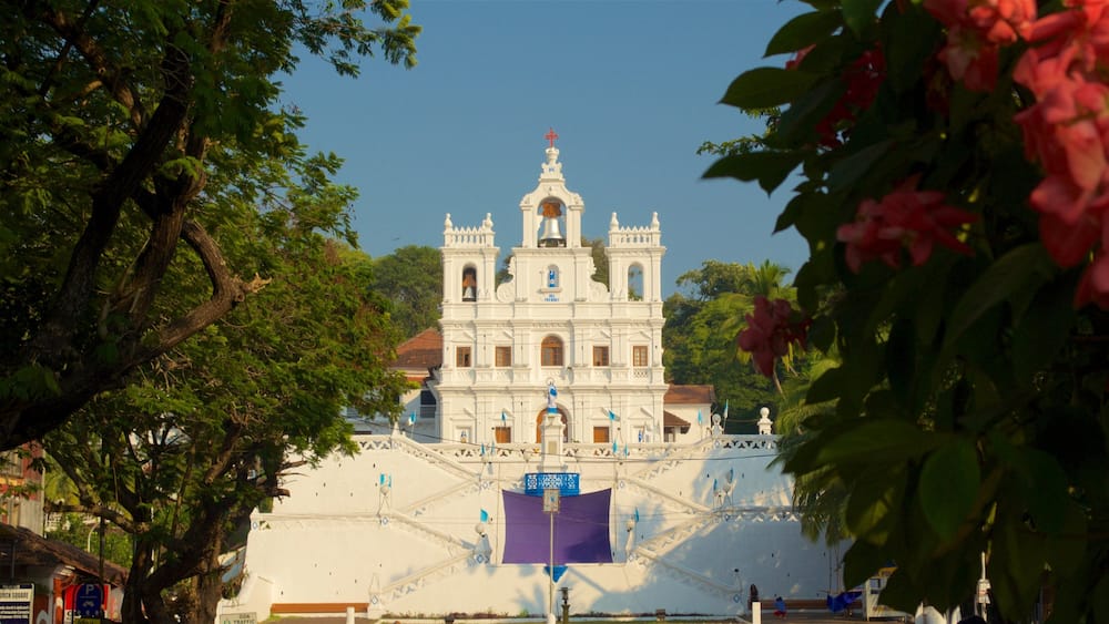 Eine weiße Kirche im Kolonialstil mit einem Glockenturm und einer Statue eines Heiligen.