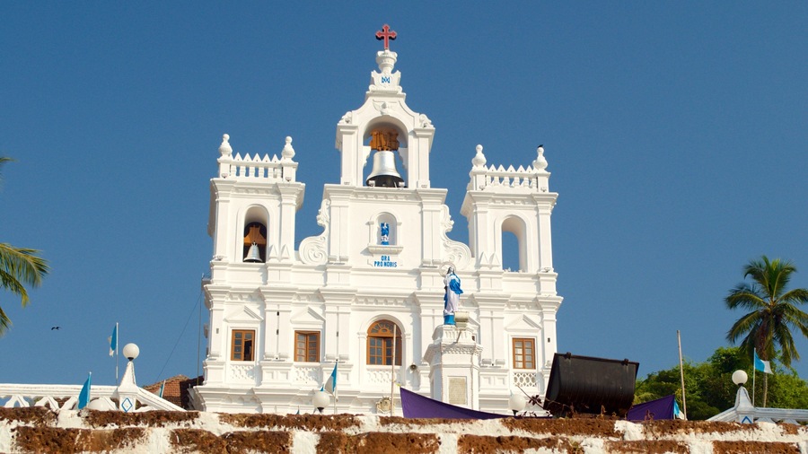A white church with a bell tower and a statue of the Virgin Mary.