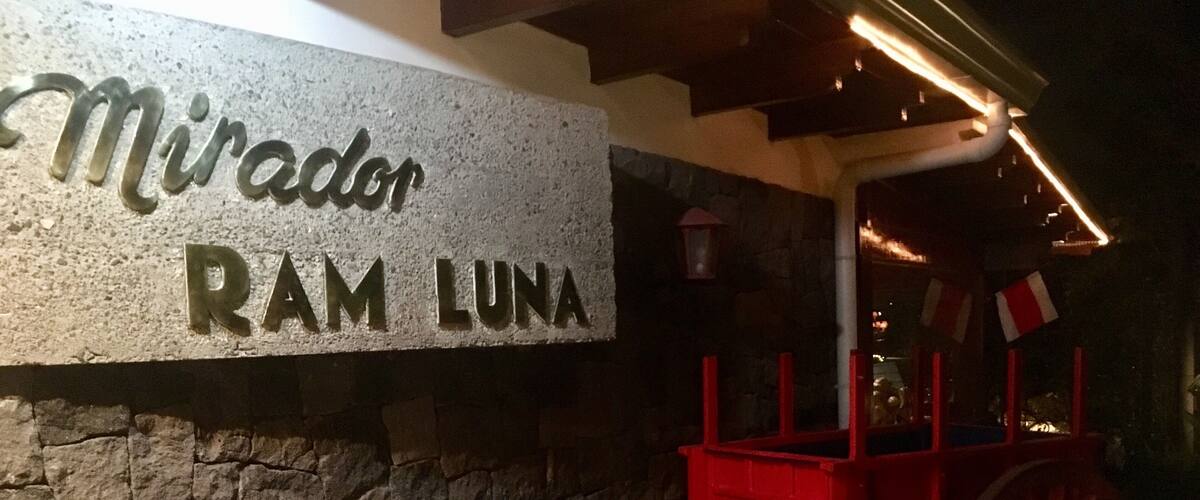 A stone sign with 'Mirador Ram Luna' engraved on it, a red cart, and a stone wall.