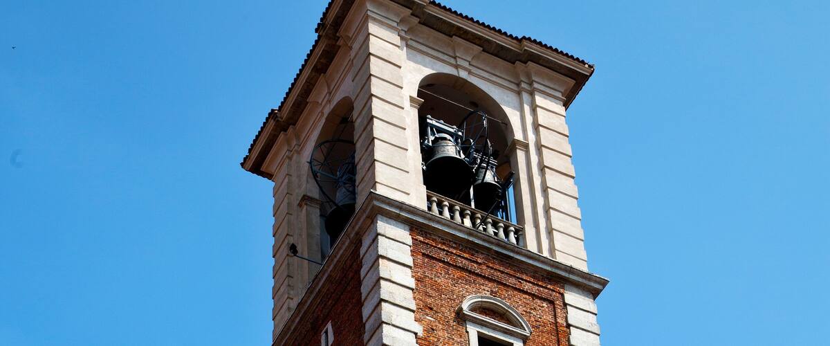 A tall brick tower with a clock and a bell.