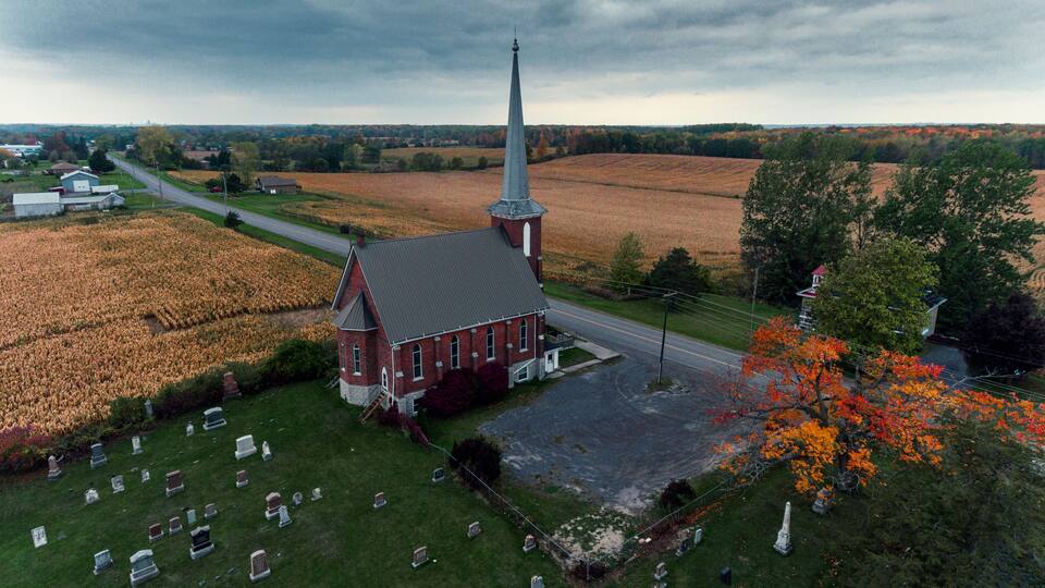 A church surrounded by a cemetery and fields.