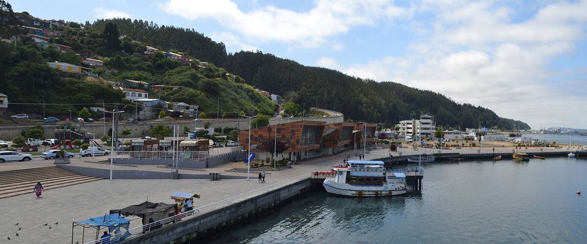 A waterfront area with a dock, a boat, and a pedestrian walkway along the water.