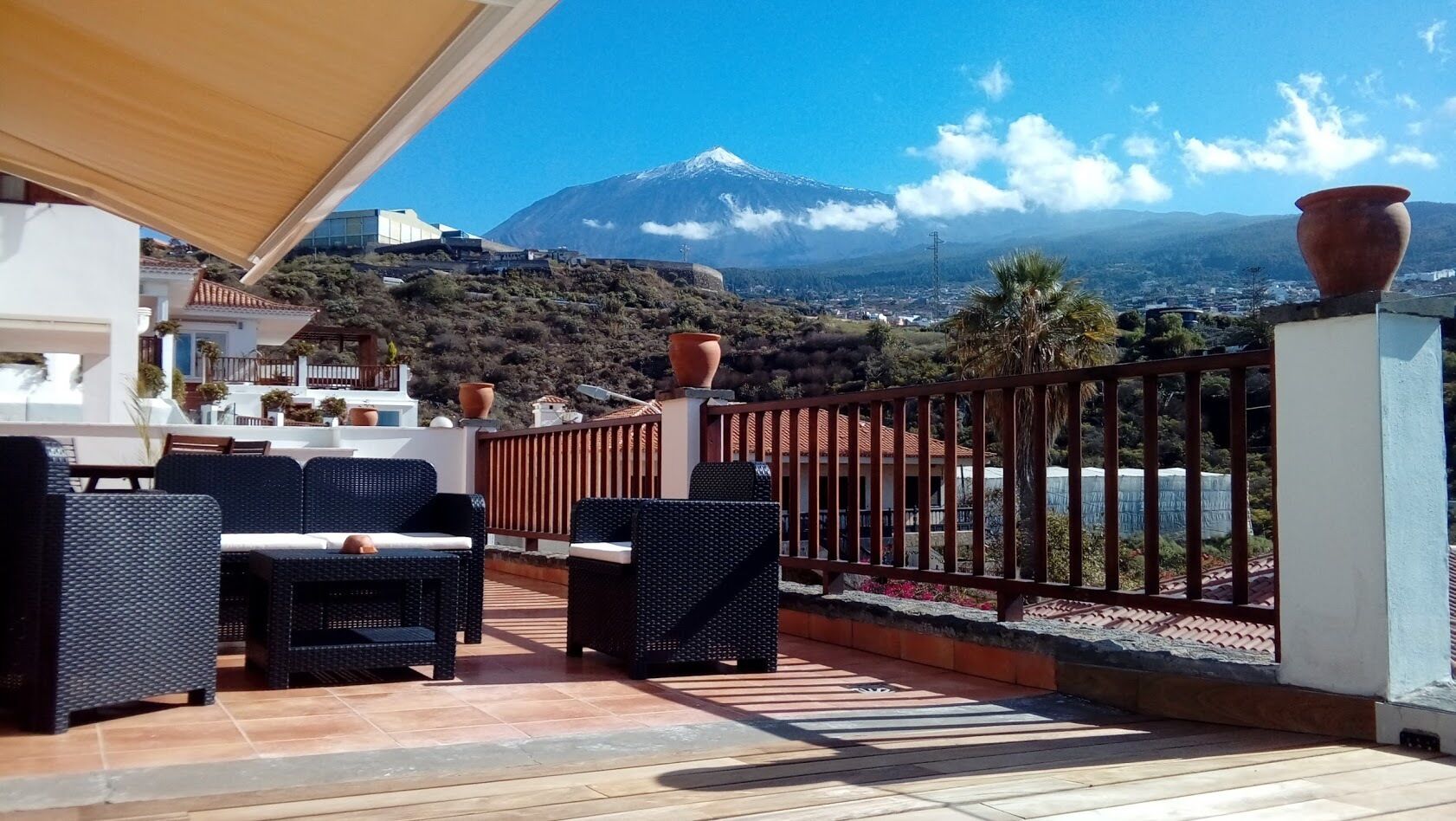 A patio with wicker furniture overlooking a mountainous landscape.