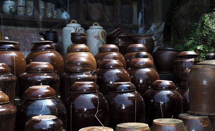A collection of traditional pottery, including various shapes and sizes, displayed against a rustic backdrop.